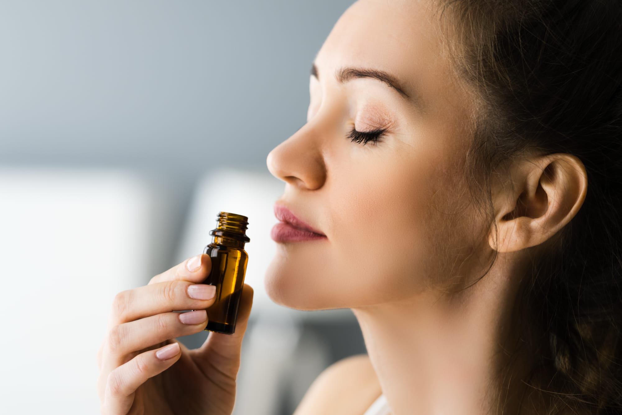 Donna che utilizza olio essenziale per aromaterapia e benessere emotivo in un momento di relax