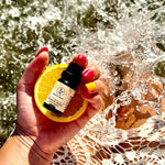 Olio essenziale di Arancia Dolce Aroma Bano tenuto in mano all’aperto con fetta di arancia