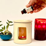 Olio essenziale di Lavanda Aroma Bano versato in un bruciatore di essenze con candela accesa