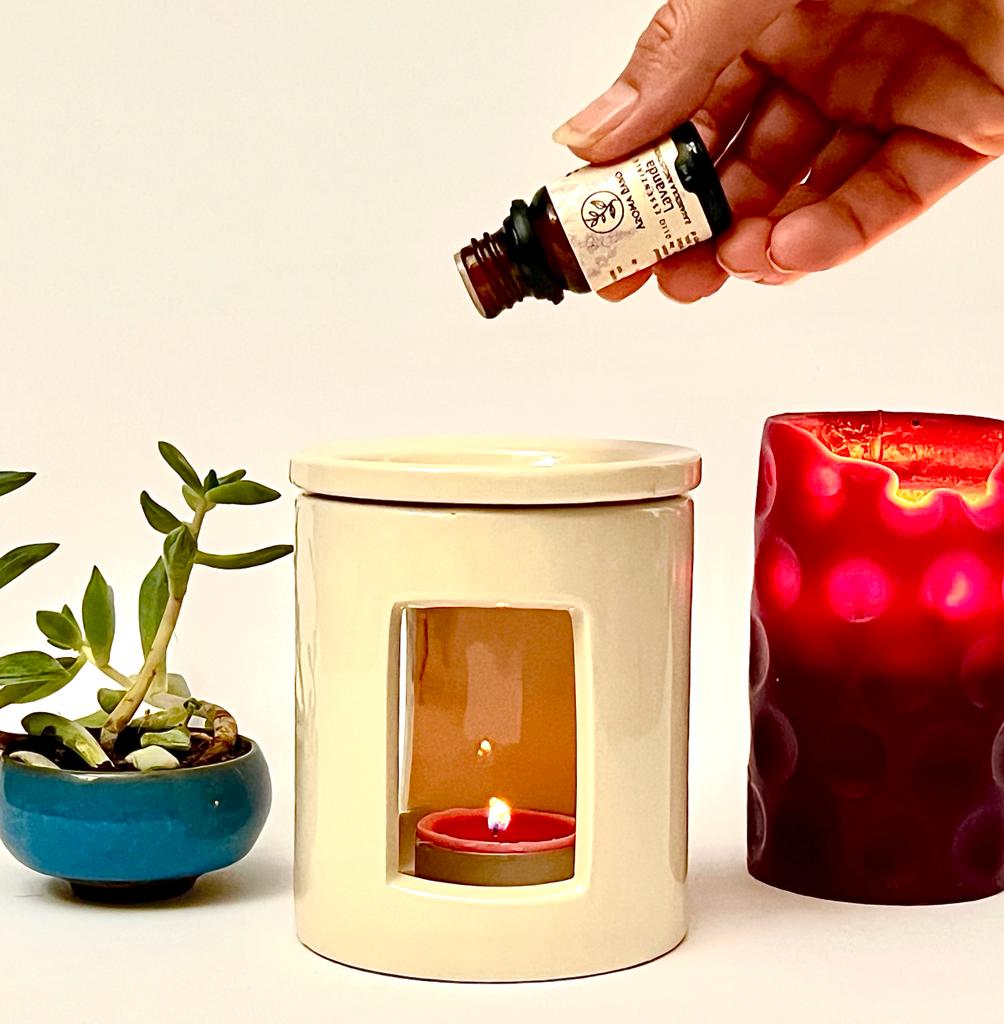 Olio essenziale di Lavanda Aroma Bano versato in un bruciatore di essenze con candela accesa
