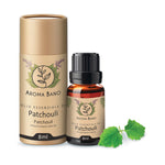 Confezione e bottiglia da 8 ml di olio essenziale di Patchouli Aroma Bano con foglie di patchouli su sfondo chiaro